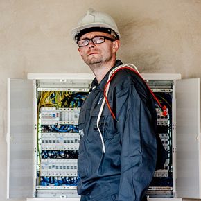 Electrician lângă un tablou electric industrial